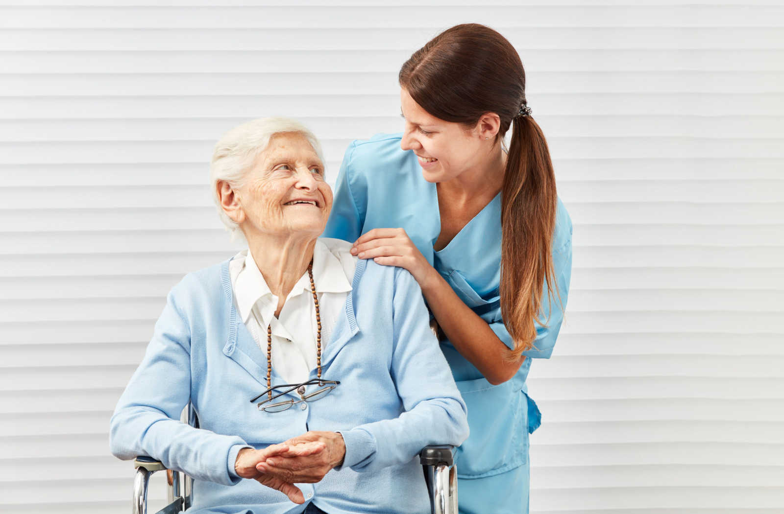 A senior woman sitting on a chair and having a conversation with a nurse.