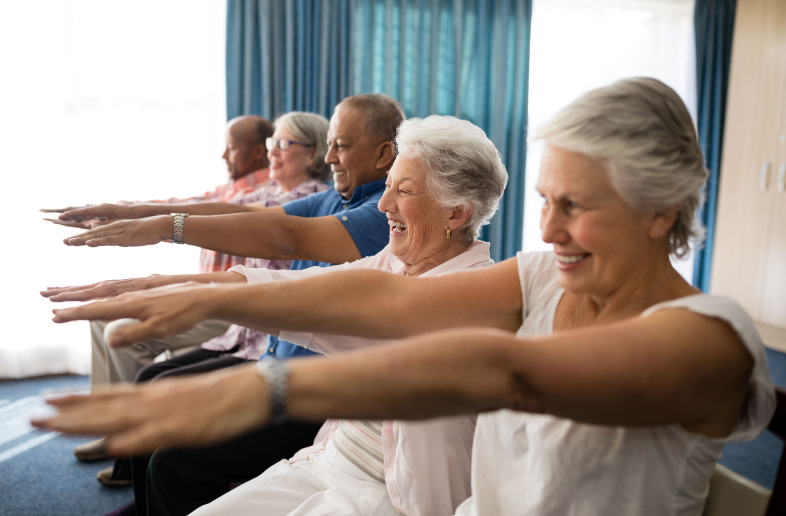 A group of seniors sitting, smiling and exercising together