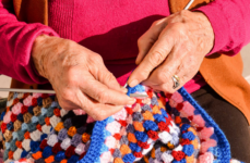A senior woman knitting a colorful sweater.