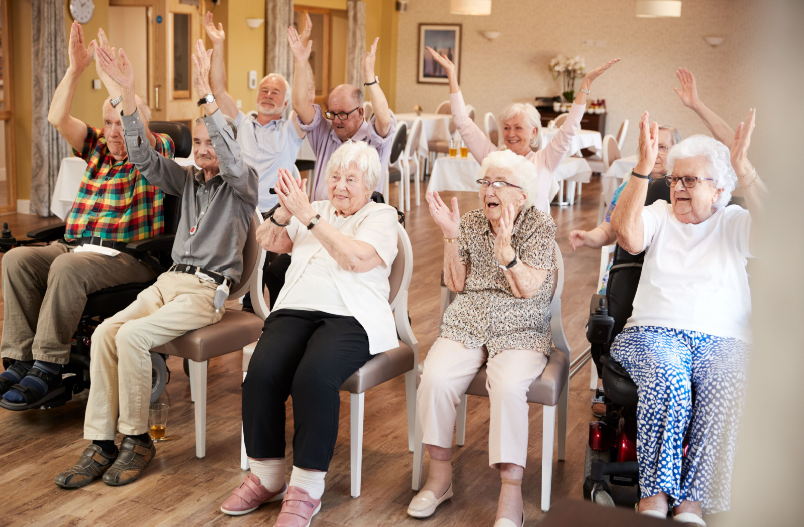A group of seniors in a senior living facility sitting and exercising together.