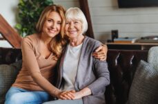 An adult daughter embracing her senior mother while they both smile