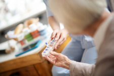 Aged woman taking pills from a pill sorter.